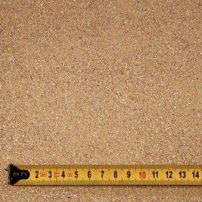 Nahaufnahme von Fugensand (Quarzsand) in Beige mit einer Körnung von 2-4 mm. Der Sand ist Rundkorn, feuergetrocknet und fein, ideal für Pflasterfugen und Gartengestaltungen. Der Maßstab zeigt die Korngröße deutlich. Perfekt geeignet für den Einsatz in der Steiermark, online kaufen oder bestellen bei leber.at.